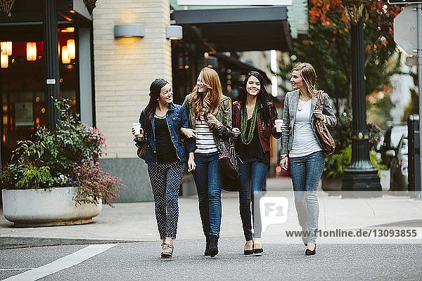 Glückliche Freundinnen unterhalten sich beim Gehen auf der Straße