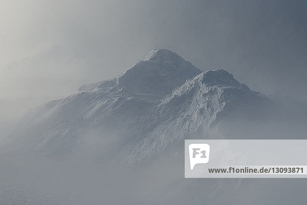 Idyllische Aussicht auf schneebedeckte Berge bei nebligem Wetter