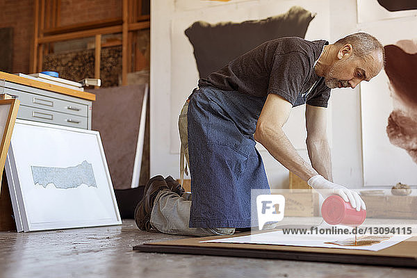 Full length of male artist making painting in workshop