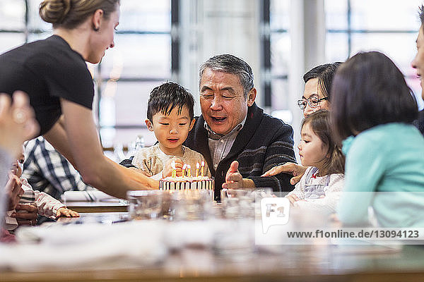 Waitress placing cake at table for family in restaurant