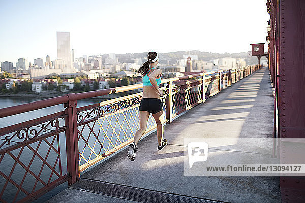 Rear view of determined sporty woman running on bridge