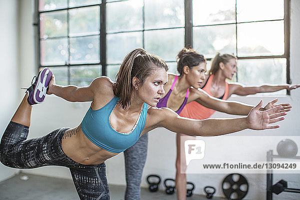 Sportlerinnen  die im Fitnessstudio die Yoga-Pose eines Tänzers üben