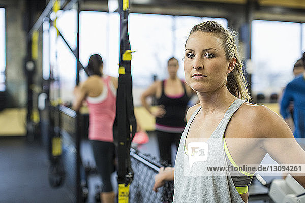 Portrait of woman standing by resistance band in gym