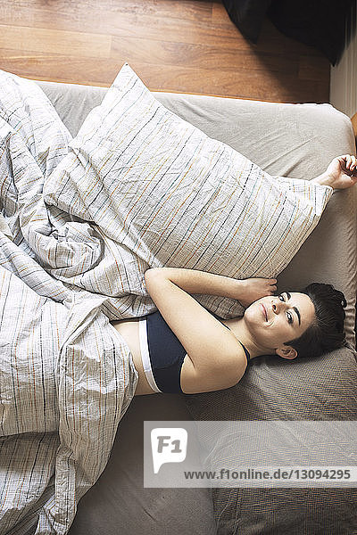 Hochwinkelporträt einer Frau  die zu Hause auf dem Bett liegt