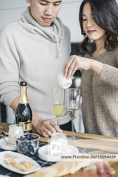 Woman with boyfriend making drink at table in kitchen