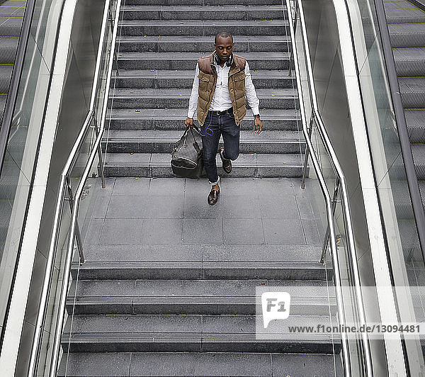 Hochwinkelaufnahme eines Mannes mit einer Tasche  der auf den Stufen einer U-Bahn-Station geht
