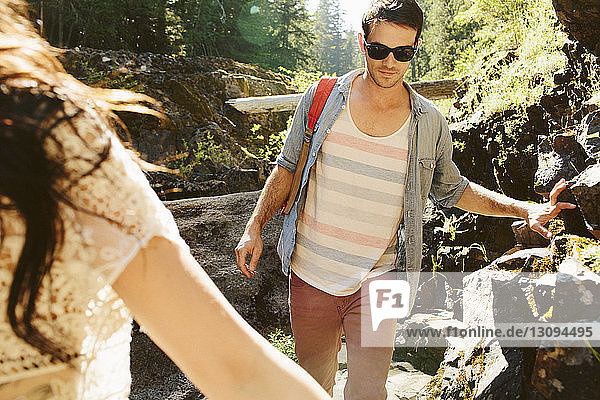 Cropped hand of woman hiking with male friend in forest