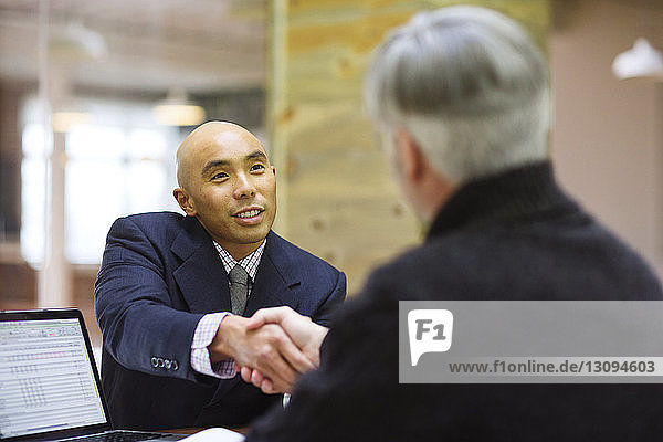 Geschäftsleute schütteln sich bei einer Besprechung im Büro die Hand