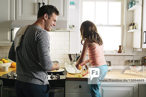 Glückliche Vater und Tochter bereiten zu Hause in der Küche Essen zu