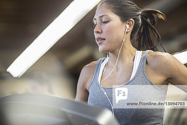 Selbstbewusste Frau  die Musik hört  während sie im Fitnessstudio auf dem Laufband trainiert
