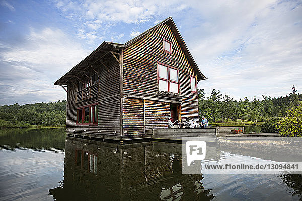 Freundin entspannt sich am Holzhaus am See gegen den Himmel