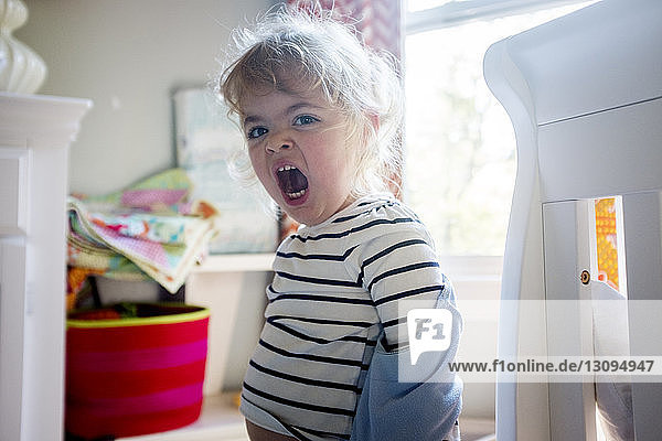 Portrait of baby girl yawning while standing at home