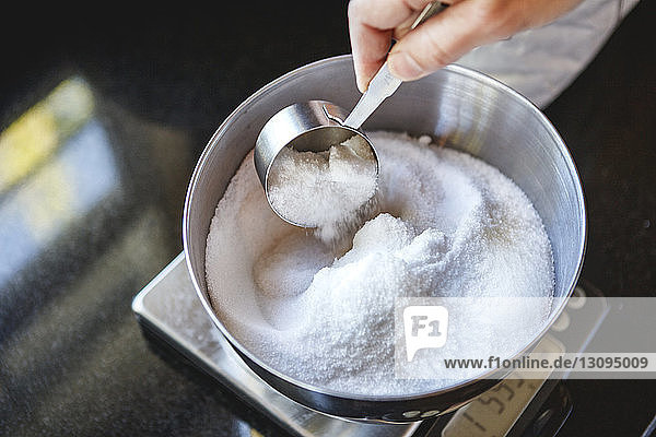 Ausgeschnittenes Bild einer Frau  die Pulver auf einer Gewichtsskala an der Küchentheke mischt