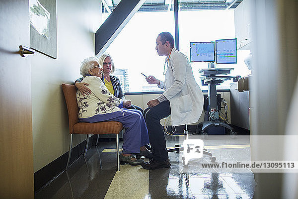 Weibliche Patientin mit Tochter im Gespräch mit männlichem Arzt auf der Krankenhausstation