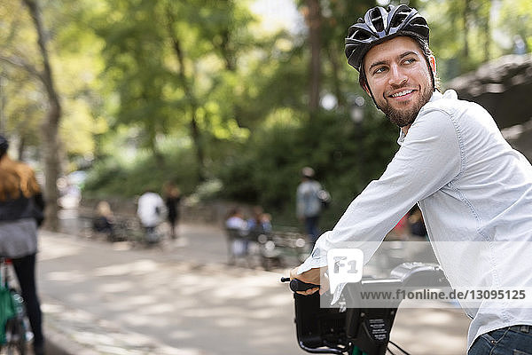 Man looking away while riding bicycle with girlfriend in park