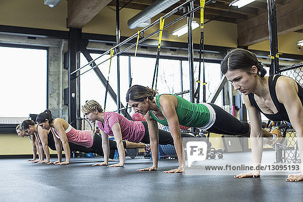 Frauen beugen sich und trainieren mit Widerstandsbändern im Fitnessstudio