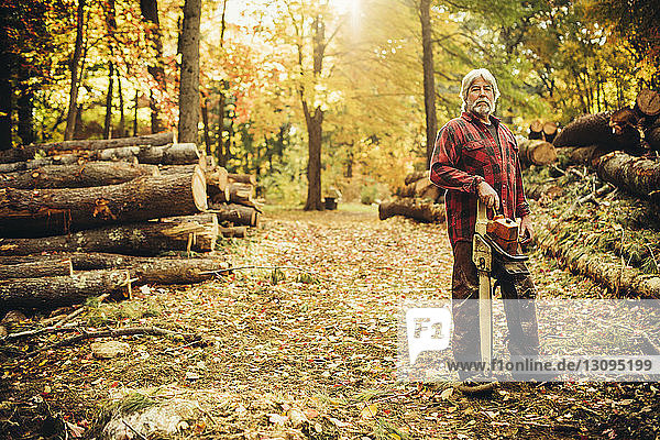 Porträt eines selbstbewussten Holzfällers mit Kettensäge im Wald