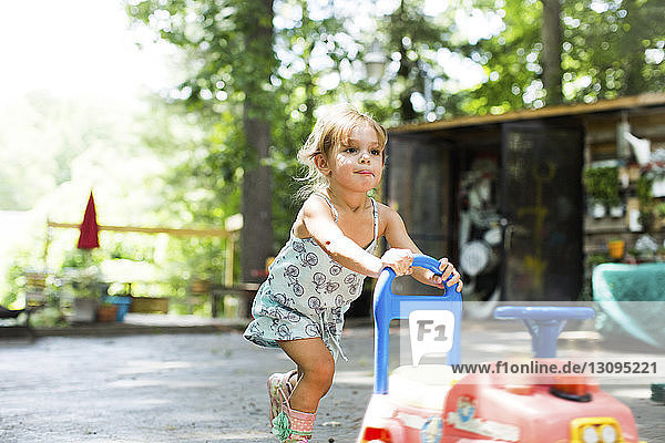 Süßes Mädchen schiebt Spielzeugauto im Garten