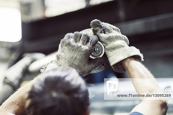 Rückansicht eines Arbeiters mit Handschuhen bei der Arbeit an Maschinen in der Industrie