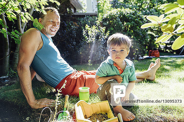 Porträt eines Jungen  der mit seinem Vater im Garten sitzt