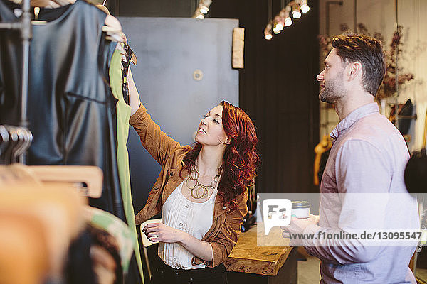 Lächelnder Besitzer zeigt Kleidungsstücke einem männlichen Kunden im Laden