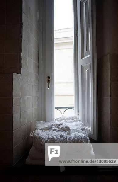 Auf die Fensterbank gestapelte Bademäntel im Badezimmer