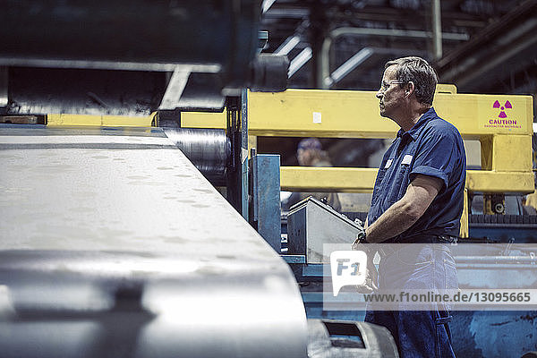 Handarbeiter betrachtet Maschinen zur Herstellung von Stahlblech in einer Fabrik