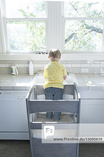 Rückansicht eines Jungen  der zu Hause am Badezimmer-Waschbecken steht