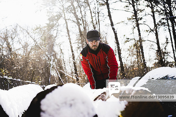 Low angle view of worker standing by snow covered fallen trees in backyard
