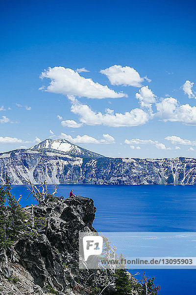 Mid distance view of hiker sitting on rocks at Crater Lake National Park