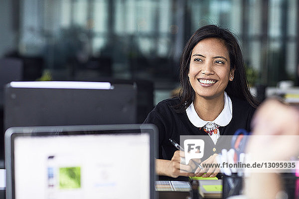 Smiling businesswoman looking away while working in office