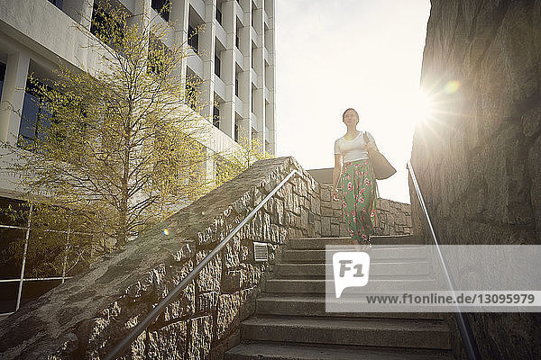 Niedrigwinkelansicht einer Frau  die sich an einem sonnigen Tag auf Stufen gegen den Himmel bewegt