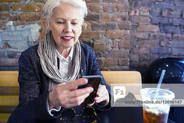 Ältere Frau benutzt Smartphone im Straßencafé