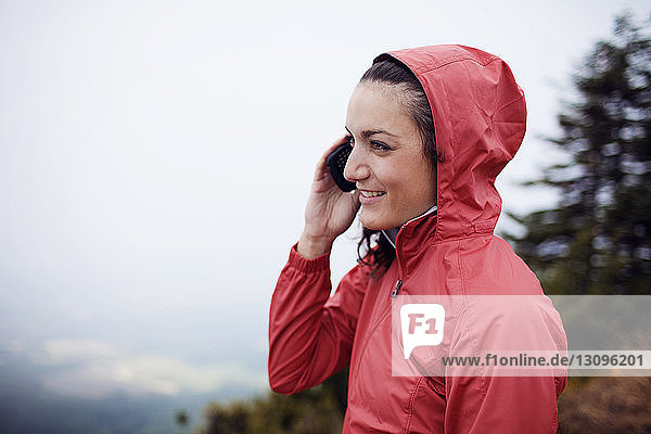 Happy female hiker talking on phone