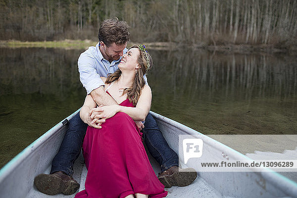 Glückliches junges Paar sitzt im Kanu auf dem See