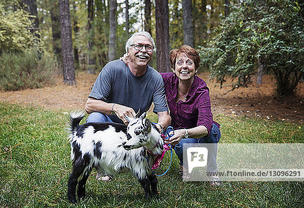 Mann und Frau kauern mit Ziege im Wald