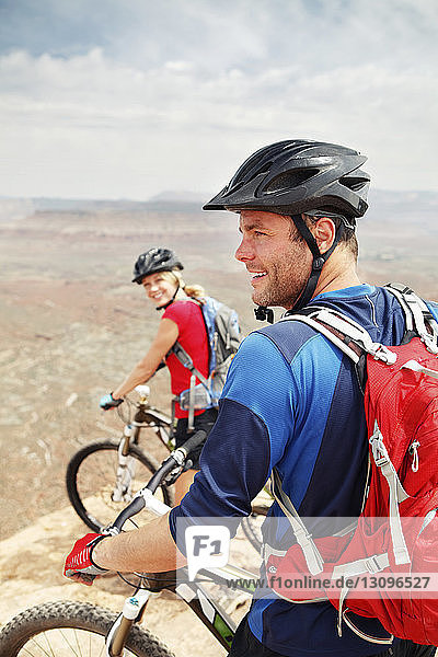 Happy couple standing with bicycles on cliff