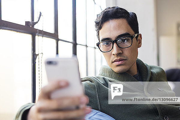 Businessman using phone while sitting on sofa in office