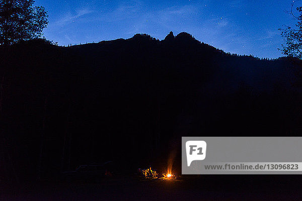 Hiker camping against silhouette mountains during night