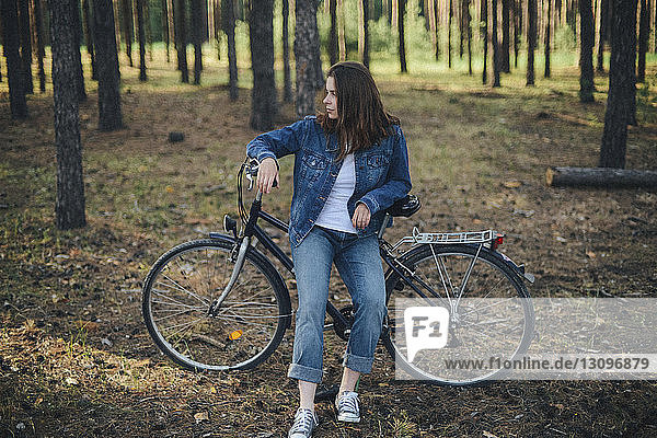 Frau schaut weg  während sie mit dem Fahrrad im Wald sitzt
