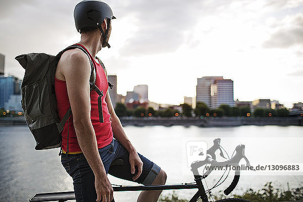 Nachdenklicher Athlet sitzt auf dem Fahrrad am See in der Stadt