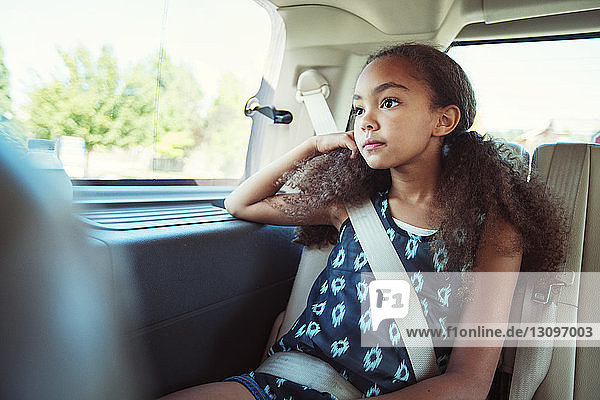 Nachdenkliches Mädchen schaut weg  während sie im Auto unterwegs ist