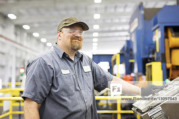 Lächelnder Arbeiter an der Maschine in einer Fabrik der Metall-Stahlindustrie