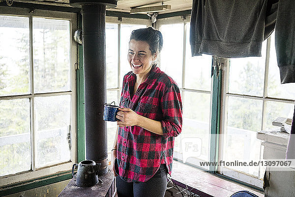 Glückliche Frau genießt Drink im Stehen in der Hütte