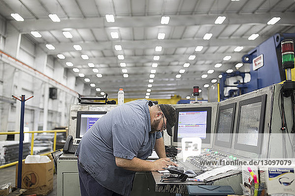 Seitenansicht eines Arbeiters  der eine Maschine in einer Fabrik der Stahlindustrie benutzt