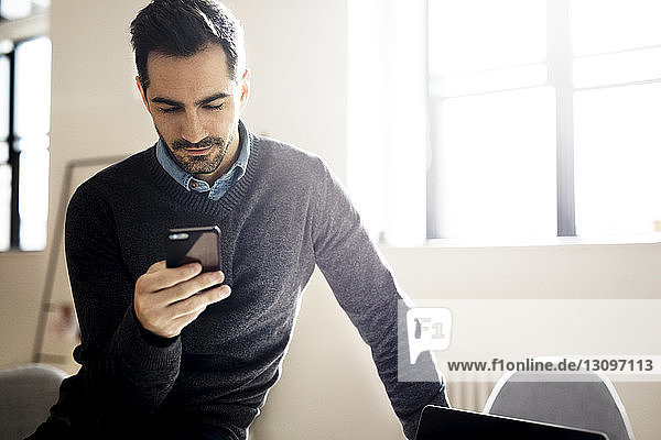 Geschäftsmann benutzt Smartphone  während er im Kreativbüro sitzt