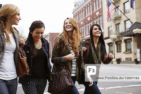 Glückliche Freundinnen unterhalten sich beim Spaziergang auf der Straße