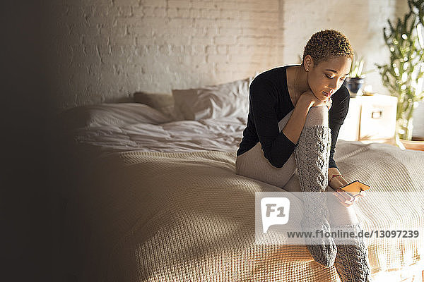 Textnachrichten der Frau über Smartphone im Schlafzimmer