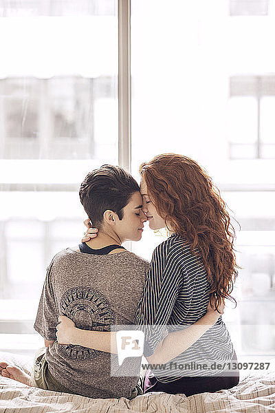 Lesbisches Paar  das zu Hause im Bett sitzt