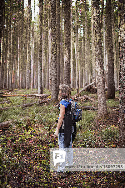 Woman carrying backpack while standing in forest